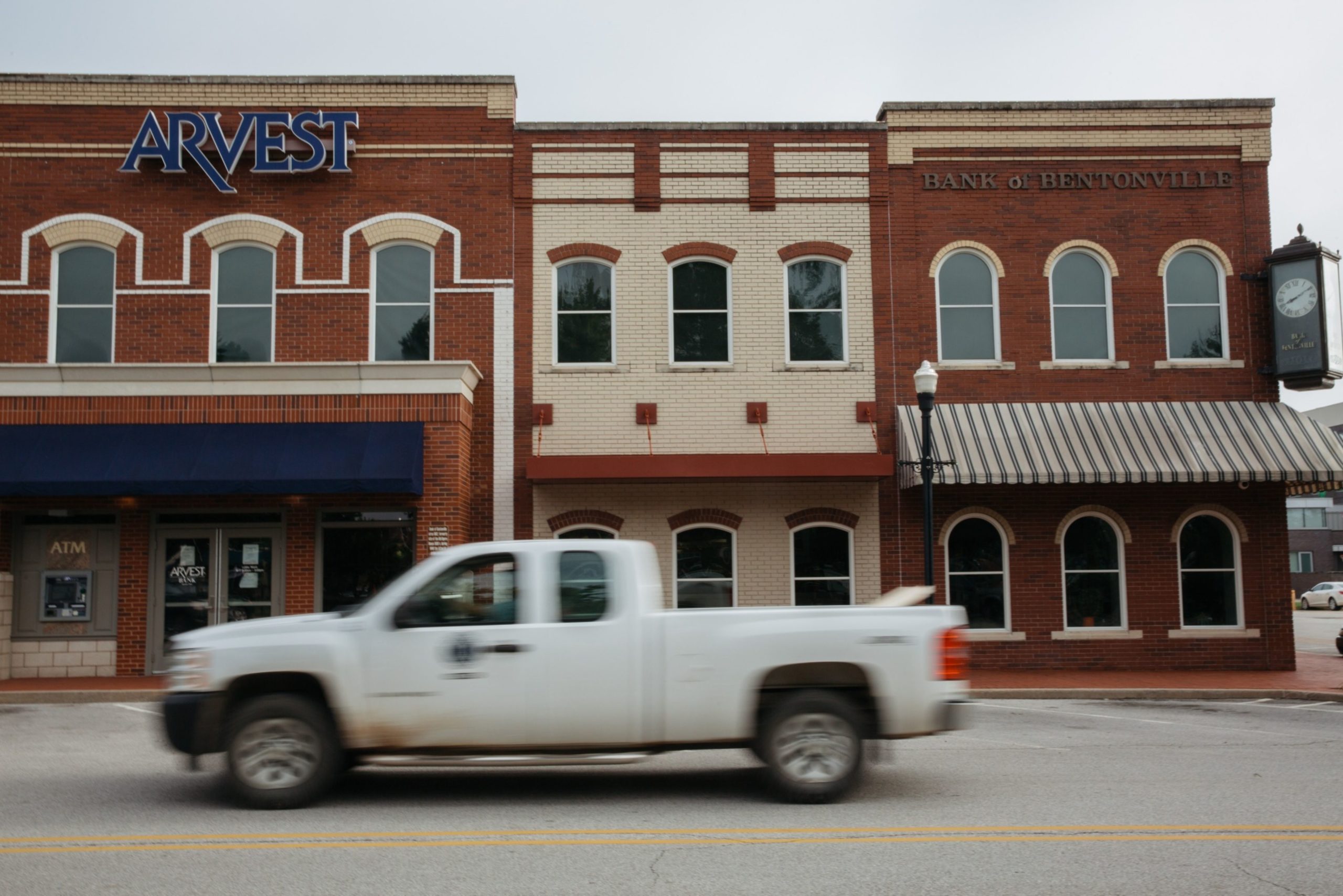 A pickup truck drives past an Arvest Bank branch on the square in Bentonville, Arkansas, U.S., on Thursday, May 28, 2020. The annual Walmart Inc. shareholder celebration attracts a varied crowd who pour money into the hotels, bars and restaurants in and around the retailer's hometown of Bentonville, Arkansas. The Covid-19 pandemic forced Walmart to pivot to a virtual gathering on June 3.